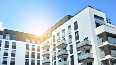 Mavi gökyüzü olan güneşli bir günde modern apartman binaları. Modern bir apartmanın ön cephesi. Güneş ışığıyla cam yüzey.