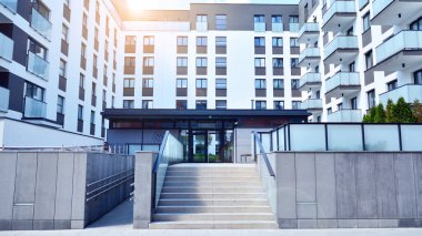 Mavi gökyüzü olan güneşli bir günde modern apartman binaları. Modern bir apartmanın ön cephesi. Güneş ışığıyla cam yüzey.