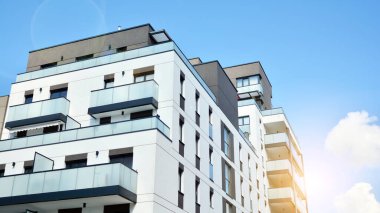 Mavi gökyüzü olan güneşli bir günde modern apartman binaları. Modern bir apartmanın ön cephesi. Güneş ışığıyla cam yüzey.