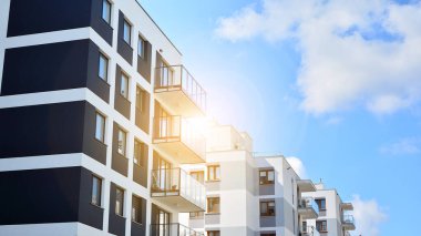 Mavi gökyüzü olan güneşli bir günde modern apartman binaları. Modern bir apartmanın ön cephesi. Güneş ışığıyla cam yüzey.