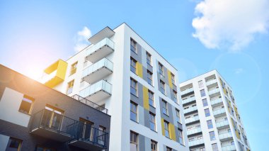 Mavi gökyüzü olan güneşli bir günde modern apartman binaları. Modern bir apartmanın ön cephesi. Güneş ışığıyla cam yüzey.