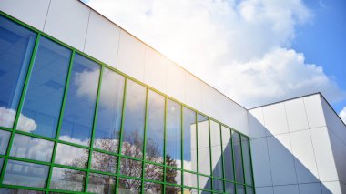 Mavi gökyüzü olan güneşli bir günde modern apartman binaları. Modern bir apartmanın ön cephesi. Güneş ışığıyla cam yüzey.