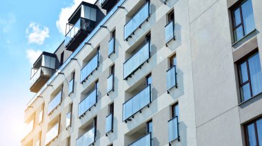 Mavi gökyüzü olan güneşli bir günde modern apartman binaları. Modern bir apartmanın ön cephesi. Güneş ışığıyla cam yüzey.