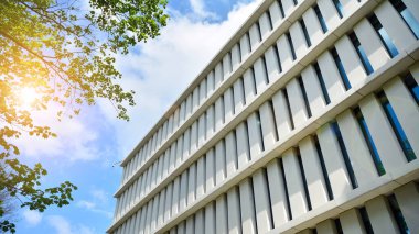 Güneş ışınlı modern mimari. Parlak güneşli bir günde, masmavi gökyüzünde güneş ışınlarıyla cam cephe.