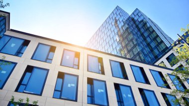 Ofis binasının alt manzarası gün doğumu, yansıma ve perspektifle kapanıyor. Güneş ışınlı modern mimari. Parlak güneşli bir günde, masmavi gökyüzünde güneş ışınlarıyla cam cephe. 