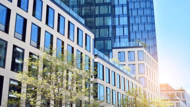 Ofis binasının alt manzarası gün doğumu, yansıma ve perspektifle kapanıyor. Güneş ışınlı modern mimari. Parlak güneşli bir günde, masmavi gökyüzünde güneş ışınlarıyla cam cephe. 