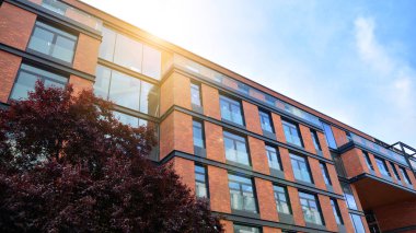 Mavi gökyüzü olan güneşli bir günde modern apartman binaları. Modern bir apartmanın ön cephesi. Güneş ışığıyla yüzeye.