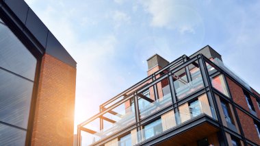 Mavi gökyüzü olan güneşli bir günde modern apartman binaları. Modern bir apartmanın ön cephesi. Güneş ışığıyla yüzeye.