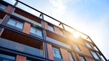 Mavi gökyüzü olan güneşli bir günde modern apartman binaları. Modern bir apartmanın ön cephesi. Güneş ışığıyla yüzeye.