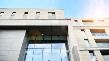 Ofis binasının alt manzarası gün doğumu, yansıma ve perspektifle kapanıyor. Güneş ışınlı modern mimari. Parlak güneşli bir günde, masmavi gökyüzünde güneş ışınlarıyla cam cephe. 