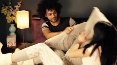 Erkek ve kadın yatakta aşık mutlu yastık kavgası yapıyor