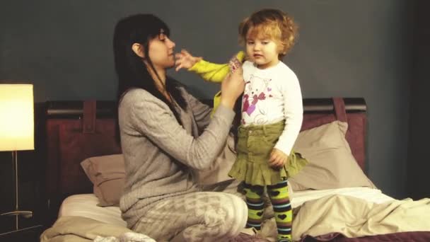 Мама одевает маленькую девочку в спальне — стоковое видео