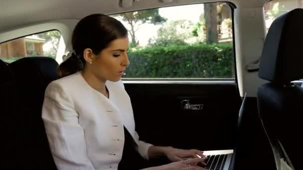 Beautiful business woman working in back of car with pc writing email. — Stock Video