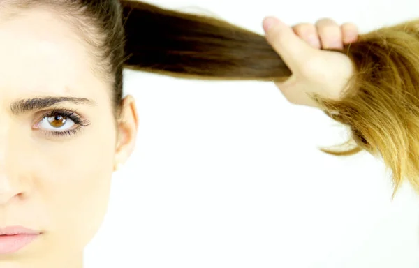 Beautiful female model pulling long hair in ponytail looking serious camera extreme closeup — Stock Photo, Image