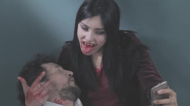 Funny female vampire taking selfie with cell phone holding dead man — Stock Video