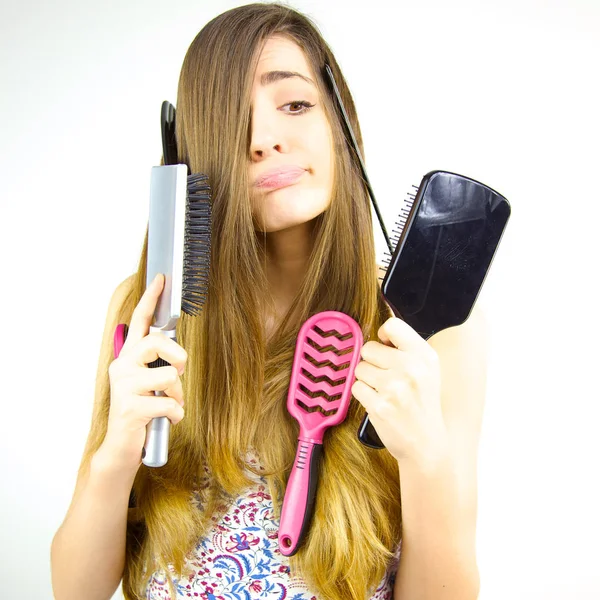 Femme faisant des grimaces drôles ne sachant pas quoi faire avec ses cheveux et ses brosses — Photo