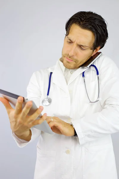 Pohledný doktor na telefonu při práci s tabletem — Stock fotografie