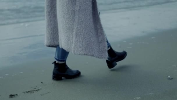 Концепция грусти женщина ходит перед диким океаном в зимнем замедленном движении крупным планом ног ходьба — стоковое видео