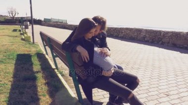 Okyanus adam hamile karnına tutarak önünde bankta oturmuş rahatlatıcı aşık Çift