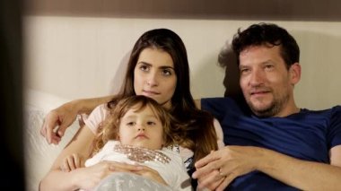 Mutlu bir aile yatakta uzaktan kumandayla televizyon izlerken eğleniyor.