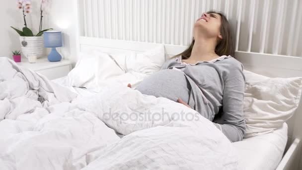 Screaming pregnant woman feeling pain in bed at home — Stock Video