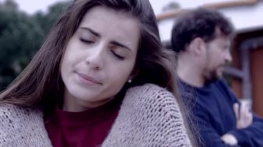 Kızgın adam üzgün kız arkadaşına bakıyor.