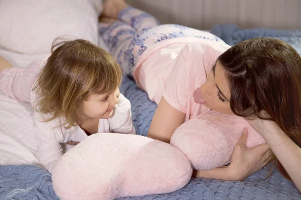 Söt liten flicka chattar i säng med syster berätta hemligheter gör tungor — Stockfoto