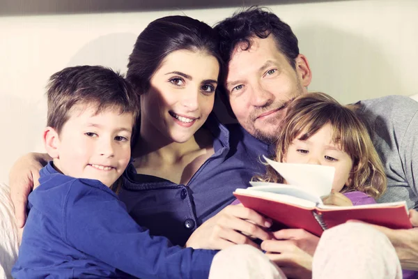 Família feliz na cama relaxante sorrindo olhando câmera — Fotografia de Stock