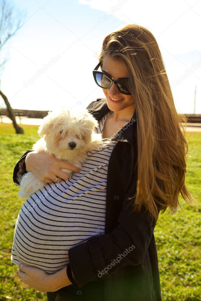 Happy pregnant woman with puppy siamese dog in park