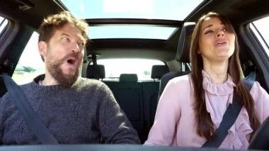 Birbirine aşık mutlu bir çift araba sürerken şarkı söylerken gözlerinin içine bakar..