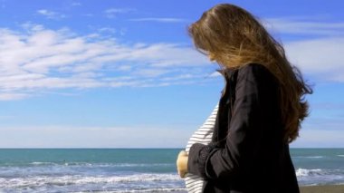 Mutlu hamile kadın okyanusun önünde dinleniyor.