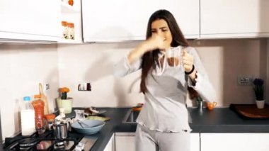 Mutfakta pijamalarıyla dans eden bir kadın. 