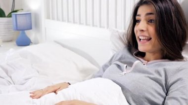 Tatlı küçük Malta köpeği yatağa atlıyor ve kadın sahibiyle yakın plan oynuyor.