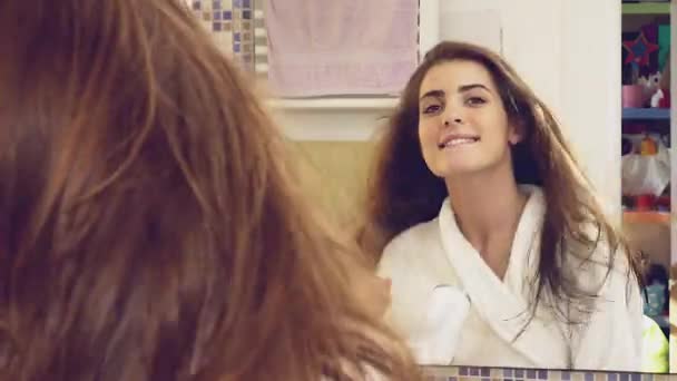 Молодая женщина в ванной дуть высушивая длинные волосы глядя камеры улыбаясь — стоковое видео