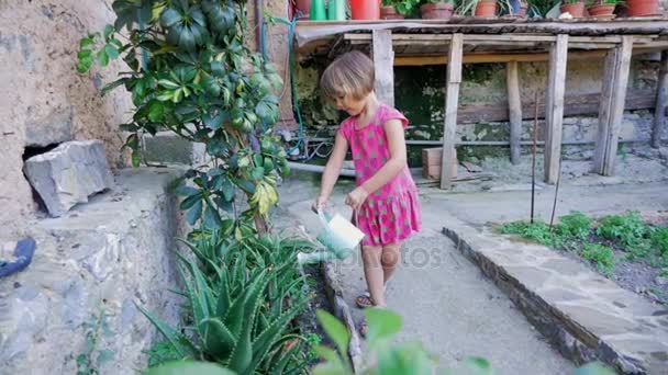 Happy cute dziewczyna dając wody do roślin w ogrodzie zwolnionym tempie — Wideo stockowe