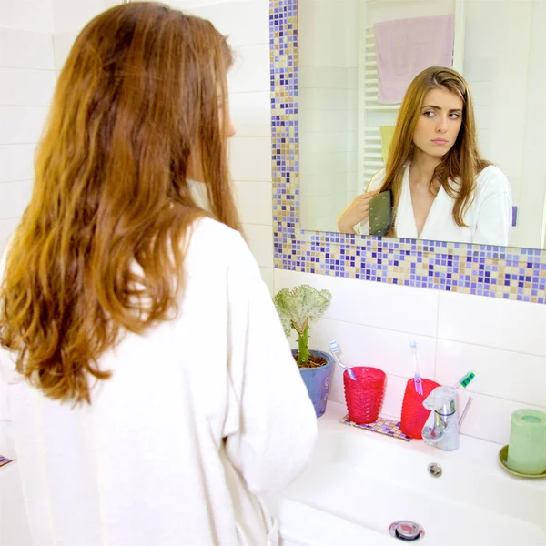 Splendida donna con accappatoio spazzolare i capelli in bagno al mattino guardando specchio — Foto Stock