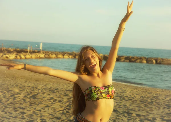 Mujer feliz sonriente frente a la playa al atardecer — Foto de Stock