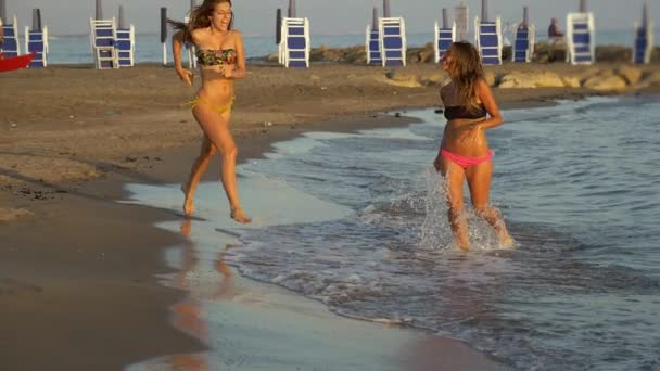 Lindas mujeres jóvenes corriendo en el océano en la playa feliz cámara lenta — Vídeo de stock