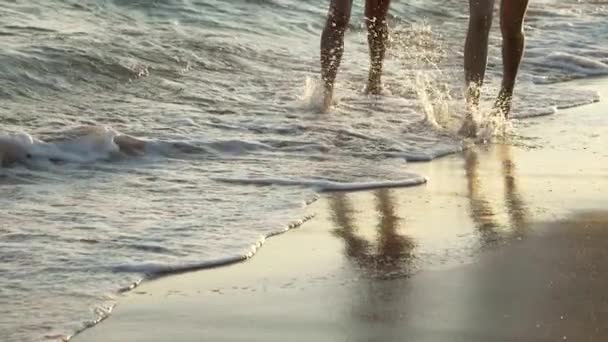 Lindas mujeres jóvenes corriendo en el océano en la playa en cámara lenta — Vídeo de stock