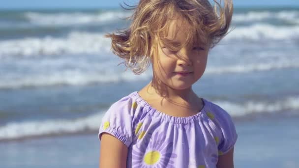 Felice bella bambina davanti all'oceano selvaggio sorridente primo piano al rallentatore — Video Stock