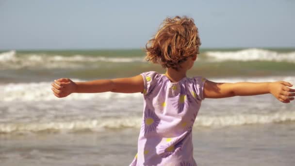 Happy beautiful little girl in front of wild ocean smiling slow motion — Stock Video