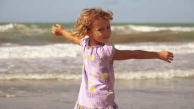 Vahşi okyanus ağır çekim gülümseyen önünde mutlu güzel küçük kız