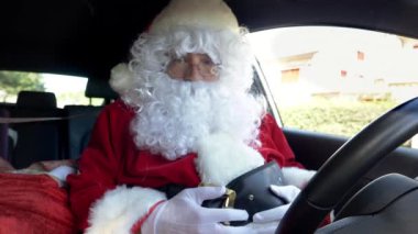 Noel Baba arabada, şapkayı ağır çekimde takıyor.