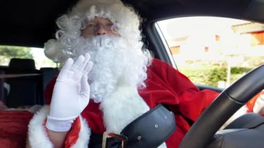 Noel Baba arabada merhaba diyor. Kameraya bakıyor.