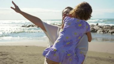 Aşk ve mutluluk kavramı, anne gün batımında kızını kumsalda tutuyor, ağır çekim.