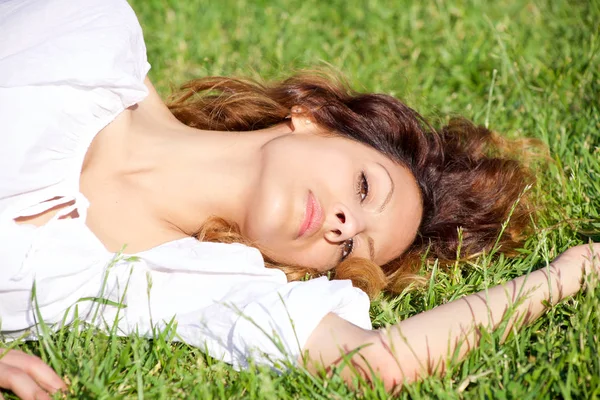 Mujer hermosa expresión intensa mirando cámara sonriendo acostado en el parque de primer plano —  Fotos de Stock