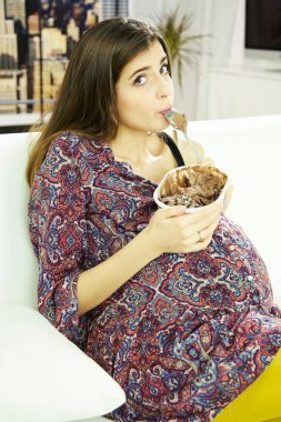 Happy beautiful pregnant woman eating ice-cream making funny face clipart