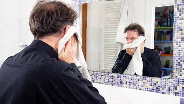 Красивый мужчина моет лицо полотенцем после бритья — стоковое видео
