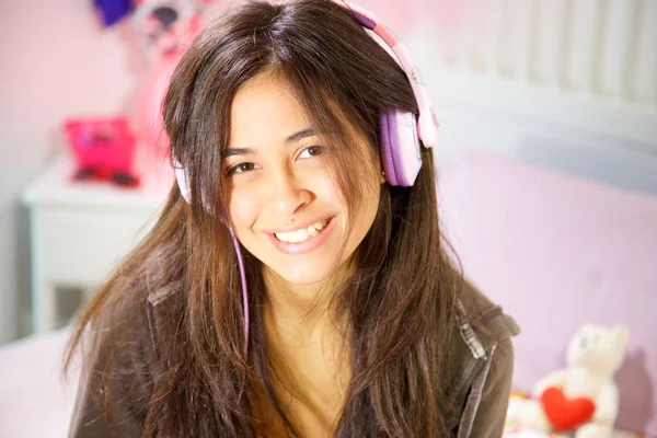 Hispanic young woman studying in bed while listening music smiling closeup — Stock Photo, Image