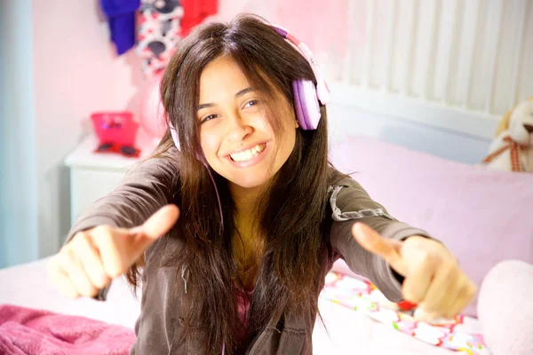 Mujer joven hispana estudiando en la cama mientras escucha música sonriendo pulgar hacia arriba — Foto de Stock